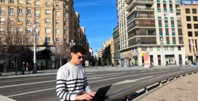 a man sitting on a bench using a laptop computer